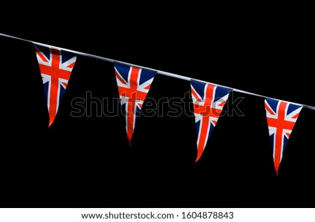 Backlit Union Jack flag bunting hanging in bright sun across a dark, distant background