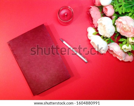 Notepad, pen and flowers on red background