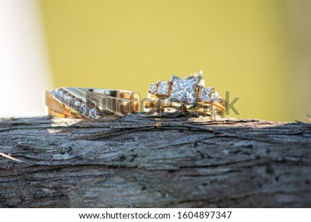 Gold wedding rings with  square diamonds side by side on wood lo