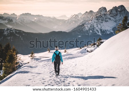 Alone girl walking down a snowy road in the Italian Alps, mountain snowy peak, valley view, hiking in snow, trekking alone, winter activities 