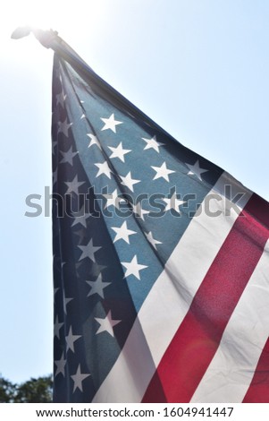American flag hanging on a flagpole on a bright blue sunny day