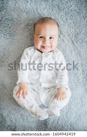 Baby boy lying and relaxing on bed white in bedroom and holding his legs. Close up of holding legs. Newborn 4 month skills concept.