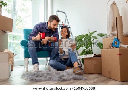 Couple in love drinking coffee and having fun while searching for home redecoration ideas using tablet computer and magazines