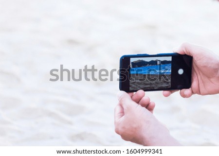 Hands take pictures of the sea landscape on a mobile phone. Beautiful view of the ocean, mountains and beach, taking a photo on a smartphone or camera. View through smartphone display