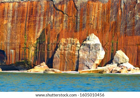 Colorful minerals deposits stripe the cliff and fallen rocks along the shore of Lake Superior at Pictured Rocks National Lakeshore in Michigan's Upper Peninsula. 