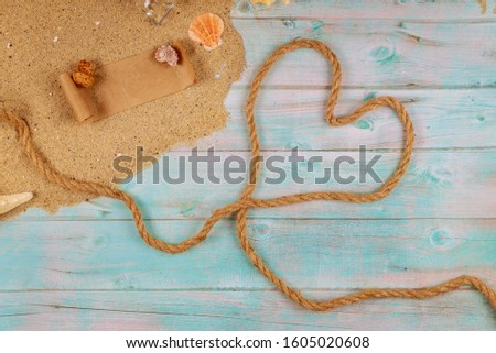 Heart made from rope on seashore with shells. Valentine day concept. Papyrus from the glass bottle with cork.