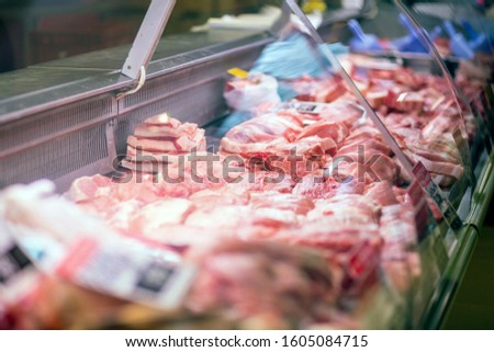 Raw pieces of meat are in the refrigerator with price tags ready for sale in the meat department of the store.