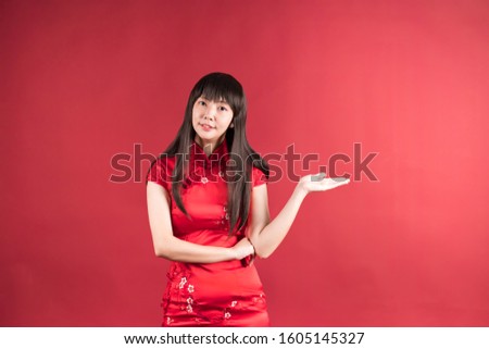 Elegant Asian woman wearing cheongsam and smiling to you to show something. Chinese new year picture.