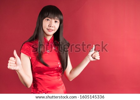Elegant Asian woman wearing cheongsam and smiling to you with gesture of good. Chinese new year picture.
