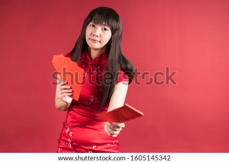 Elegant Asian woman wearing cheongsam and giving you red envelopes. Chinese new year picture.