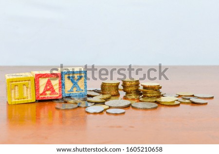Tax concept with wooden block on stacked coins. Selective focus.