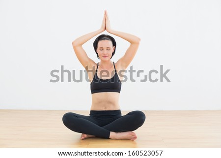 Toned young woman sitting in lotus pose with eyes closed at fitness studio