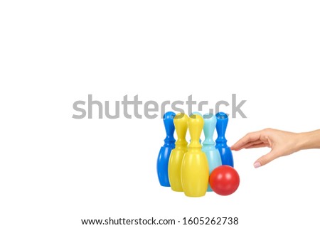 Hand with plastic colored skittles for bowling game. Kids toy. Isolated on white background. Copy space.