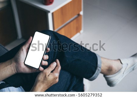 Mockup image blank white screen cell phone.man hand holding texting using mobile on sofa at home.background empty space for advertise text.people contact marketing business,technology 