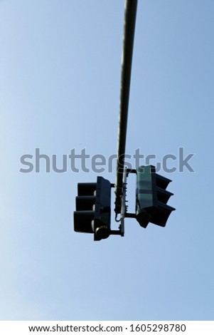 Traffic light hanging from a pole in the blue sky.
