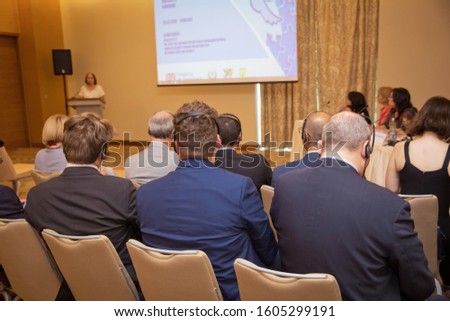 Unrecognizable man using headphones for translation during video conference . bald security guard with the headset to control people . heated debate at a conference discussion . Royalty-Free Stock Photo #1605299191