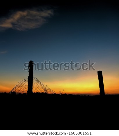 A broken fench and two pillars shot during sunset hours. Space is provided in the picture to add text.