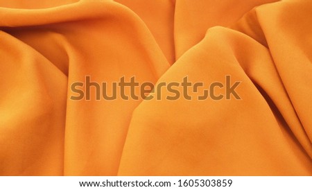 Orange background from fabric. Crumpled fabric background close-up.