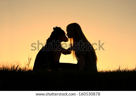 a special and serene moment as a girl is lovingly hugging her German Shepherd Dog, silhouetted against the sunsetting sky Royalty-Free Stock Photo #160530878