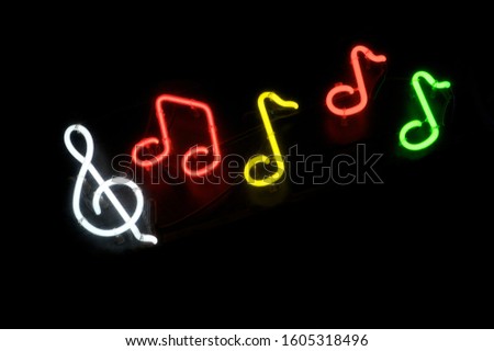 Musical notes with treble clef in colorful neon lights floating across dark background at night