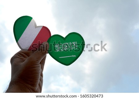 Hand holds a heart Shape Italy and Saudi Arabia flag, love between two countries