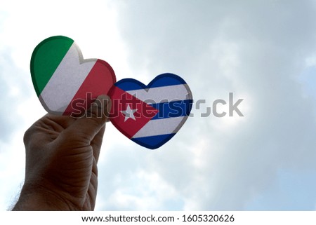 Hand holds a heart Shape Italy and Cuba flag, love between two countries