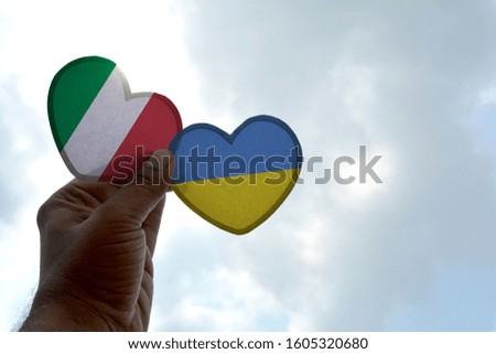 Hand holds a heart Shape Italy and Ukraine flag, love between two countries