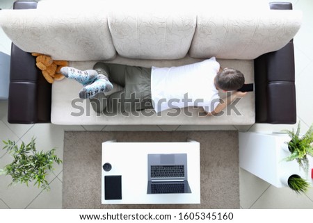 Man lie on sofa and hold modern smartphone in hand. Using mobile application concept. Social media addict