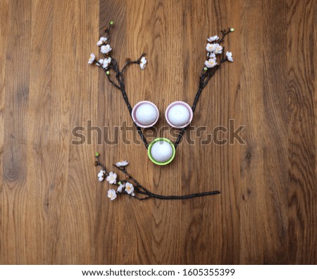 Easter eggs with branches of blooming cherry on wooden background, minimalistic concept.