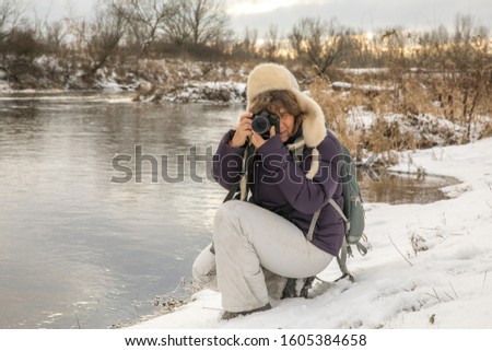 Woman making the pictures on the Bank of the Vistula river during the winter. Poland. Natura 2000