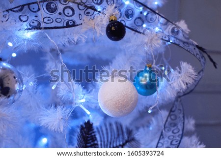 Closeup of traditional artificial Christmas tree with various ball ornament and glowing colorful garland  lights  on blurred, sparkling and fairy background
