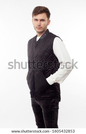 Handsome man in black vest, black jeans and boots isolated on white background.