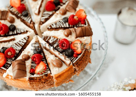 Chocolate cheesecake black and white with strawberries, raspberries, blueberries, on a glass plate. Picture for a menu or confectionery catalog