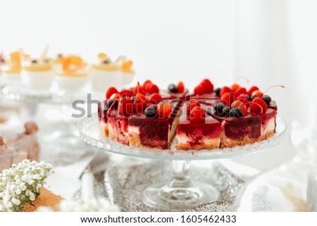 Creamy fruity cheesecake with cherry, raspberries, blueberries, on a glass plate. Picture for a menu or confectionery catalog
