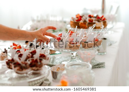 Mousse with almonds and hazelnuts, of dark chocolate in transparent plastic cup grabbed by hand. Picture for a menu or confectionery catalog