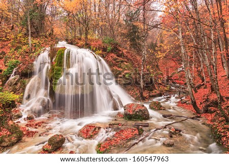 Autumn waterfall with stones in the forest