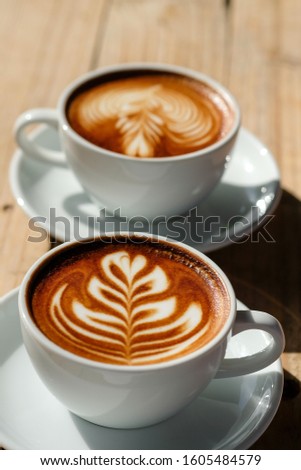 cup of hot coffee latte art and cappuccino on wood table background