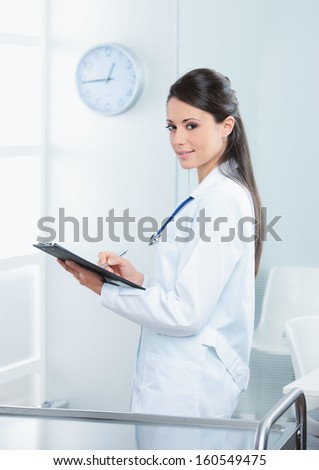 Portrait of a smiling female doctor working on her report  
