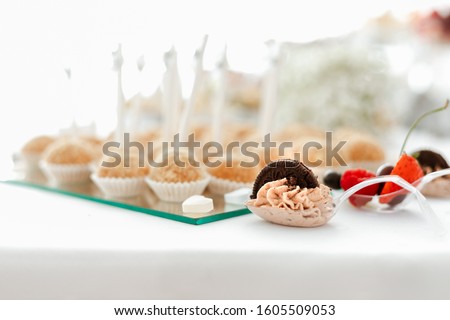 Chocolate cream spoons for a candy bar, in a plastic transparent spoon, made of milk chocolate decorated by a biscuit. Picture for a menu or confectionery catalog