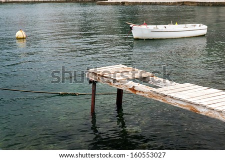 A picture of an old white boat and an wooden pier