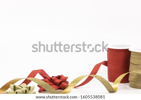 Reels of red curling ribbon and golden glitter in place for the Christmas gifts or birthday gift ribbon with knot photo on white background with text space