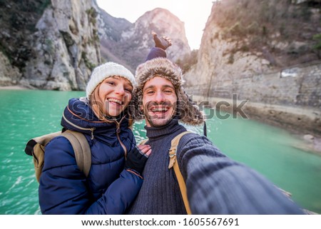 Happy couple of hikers taking a selfie with cell phone at vacation in the mountain at winter 