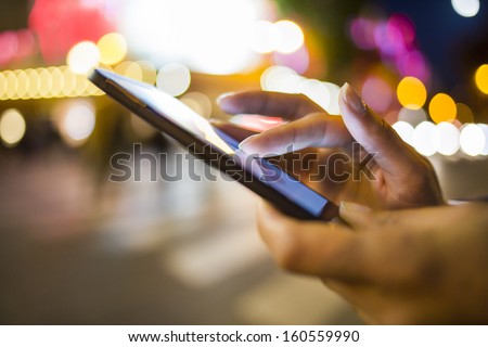 Woman using her Mobile Phone in the street, night light Background Royalty-Free Stock Photo #160559990