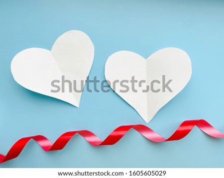 Valentine's day background.  white paper hearts and red festive ribbon on a pastel blue background.  symbol of love and valentines day concept.  pattern, flat lay, top view, copy space