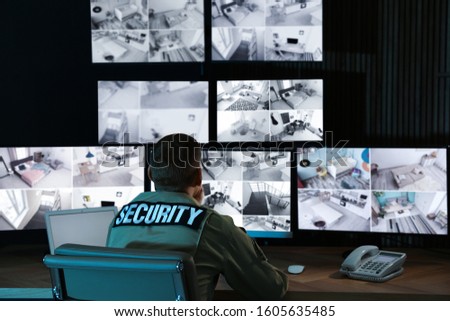 Security Guard Monitoring Video In Security Room From The