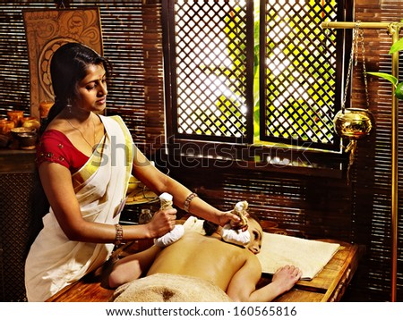 Woman having ayurvedic massage with pouch of rice.