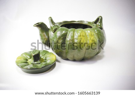 Pumpkin-shaped green kettle on a white background