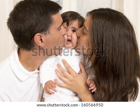 Mother and Father Kissing their Baby Girl