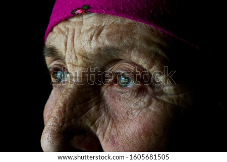 View of the old grandmother. The old grandmother looks forward with hope. Eyes with teardrops on mother's wrinkled face.