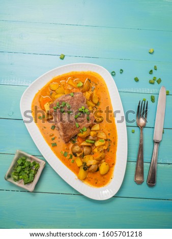 Top view of catfish fillet on colourful vegetable curry on a blue wooden background - copy space